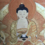 Close-up of HD giclée Shakyamuni Buddha Thangka print with orange tones and gold line details.