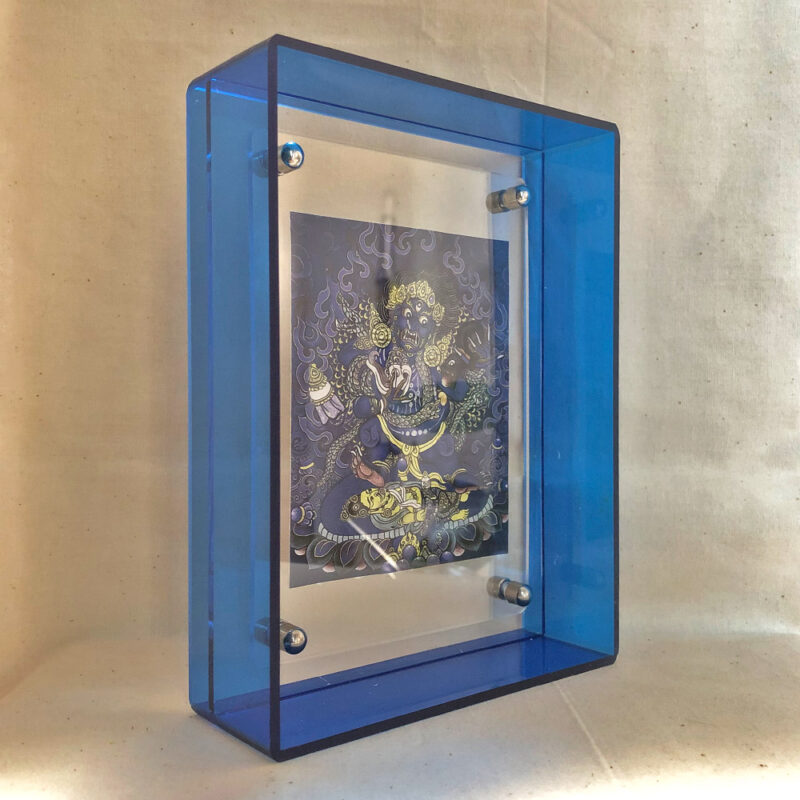 Side perspective of Indigo Black Jambhala Thangka print inside a blue translucent acrylic display frame.