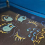 Close-up of original hand-painted gold linework and Mahakala Buddha eyes on indigo canvas.