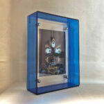 Side perspective of indigo Mahakala Buddha Eyes art inside a blue translucent acrylic frame.