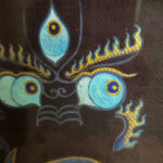 Close-up of original hand-painted gold linework and wisdom Buddha eyes on indigo canvas.
