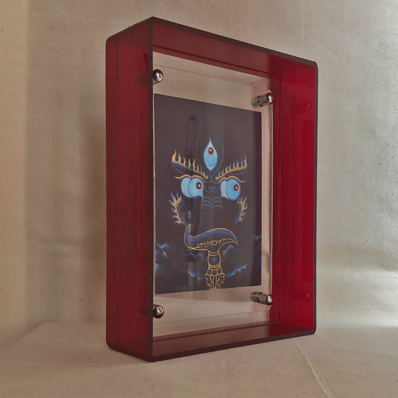 Side perspective of indigo Yamantaka Buddha Eyes art inside a red translucent acrylic frame.