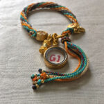 Backside view of the indigo Mahakala charm bracelet displaying the authentic brand emblem.