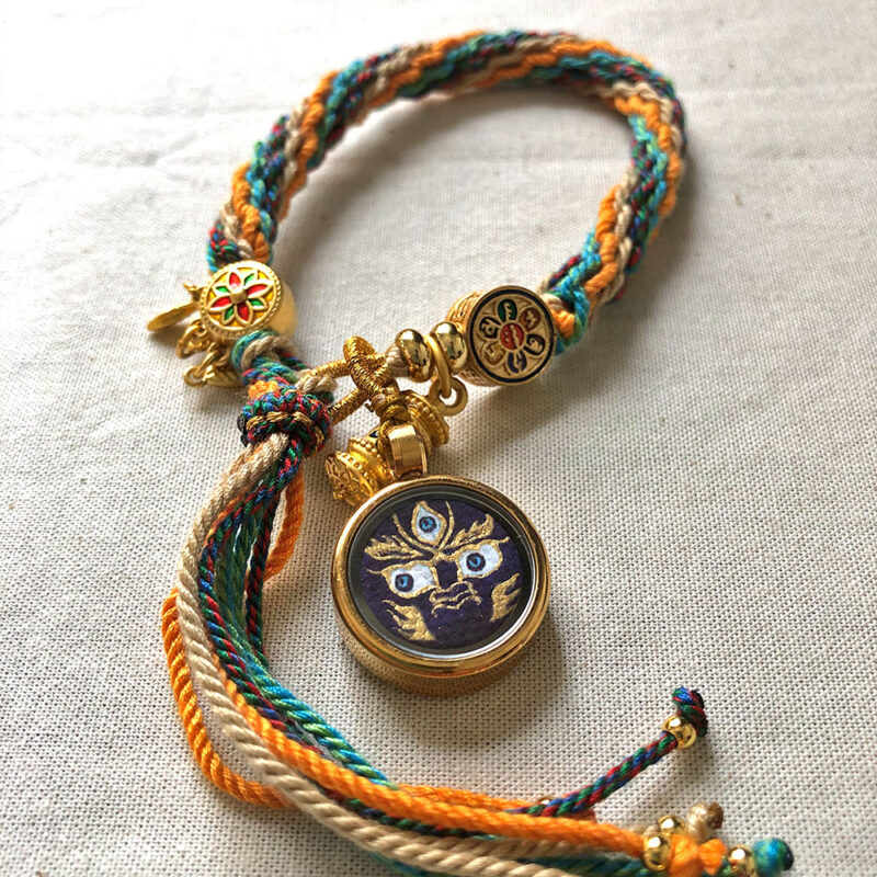 Flatlay layout of the indigo Mahakala Buddha Eyes braided cord bracelet for meditation.