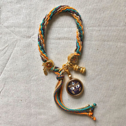 Vertical layout of the indigo Mahakala Buddha Eyes charm bracelet with woven cord.