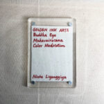 Backside of clear acrylic frame displaying artist signature card and magnetic corner screws.