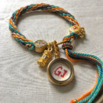 Backside view of the yellow Manjushri charm bracelet displaying the authentic brand emblem.