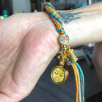 Yellow Manjushri Buddha Eyes charm bracelet worn on wrist for mental focus.