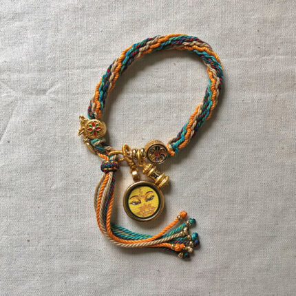 Full view of yellow Manjushri Buddha Eyes pendant and braided cord.