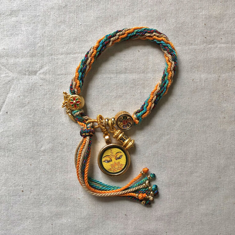 Full view of yellow Manjushri Buddha Eyes pendant and braided cord.