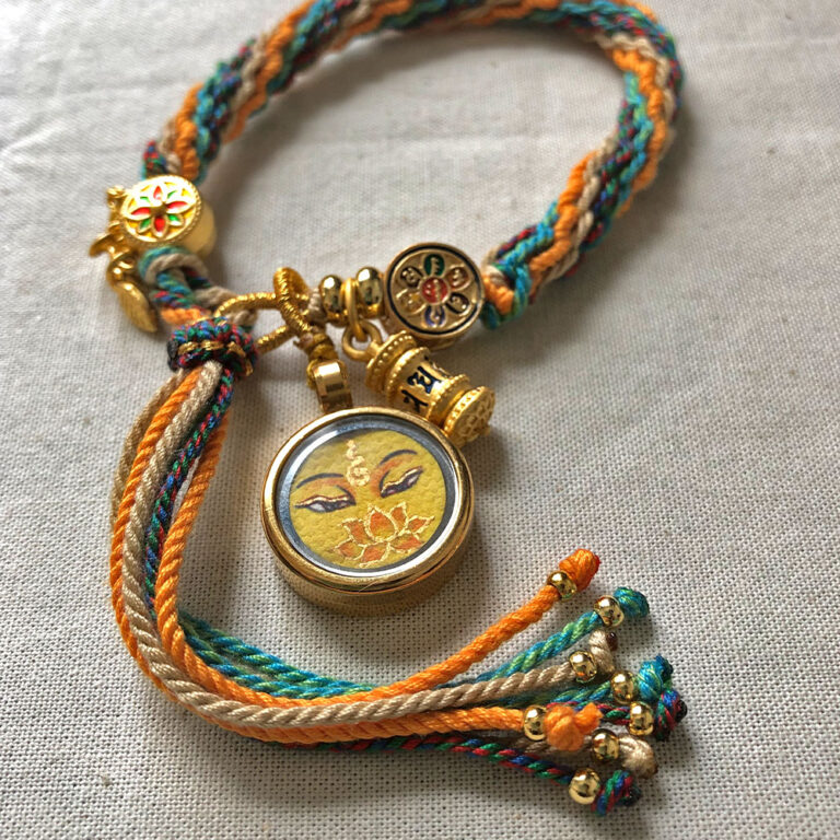 Flatlay layout of the yellow Manjushri Buddha Eyes braided cord bracelet for focus.