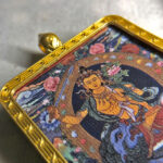 Close-up of Manjushri Bodhisattva pendant in gold Gau box for zodiac guardian meditation.