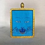 Frontal view of Medicine Buddha Eyes pendant for Throat Chakra color meditation.