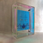 Side perspective of Medicine Buddha Eyes art inside an iridescent translucent acrylic frame.