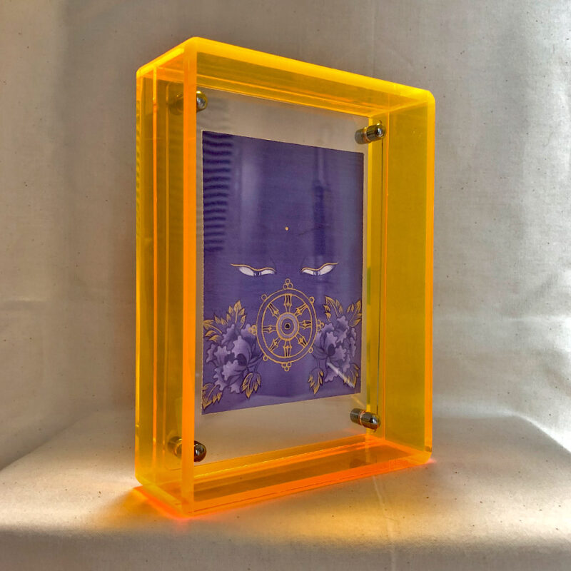 Side perspective of purple Vairochana Buddha Eyes art inside a yellow translucent acrylic frame.