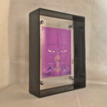 Side perspective of purple Vajrasattva Buddha Eyes art inside a grey translucent acrylic frame.