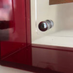 Close-up of magnetic corner screw on deep red translucent acrylic display block.
