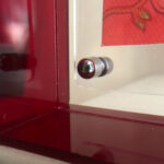 Close-up of magnetic corner screw on deep red translucent acrylic display block.
