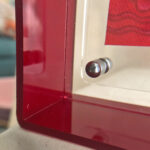 Close-up of magnetic corner screw on deep red translucent acrylic display block.