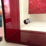Close-up of magnetic corner screw on deep red translucent acrylic display block.