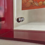 Close-up of magnetic corner screw on red translucent acrylic display block.