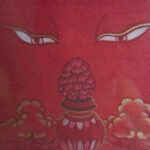 Close-up of original hand-painted gold Amitayus flask and wisdom Buddha eyes on red canvas.