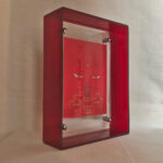 Side perspective of red Amitayus Buddha Eyes art inside a red translucent acrylic frame.