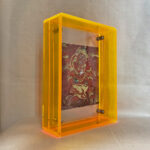 Side perspective of Red Jambhala Thangka print inside a yellow acrylic display frame.