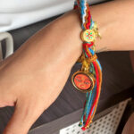Orange Shakyamuni Buddha Eyes charm bracelet worn on wrist for grounding energy.