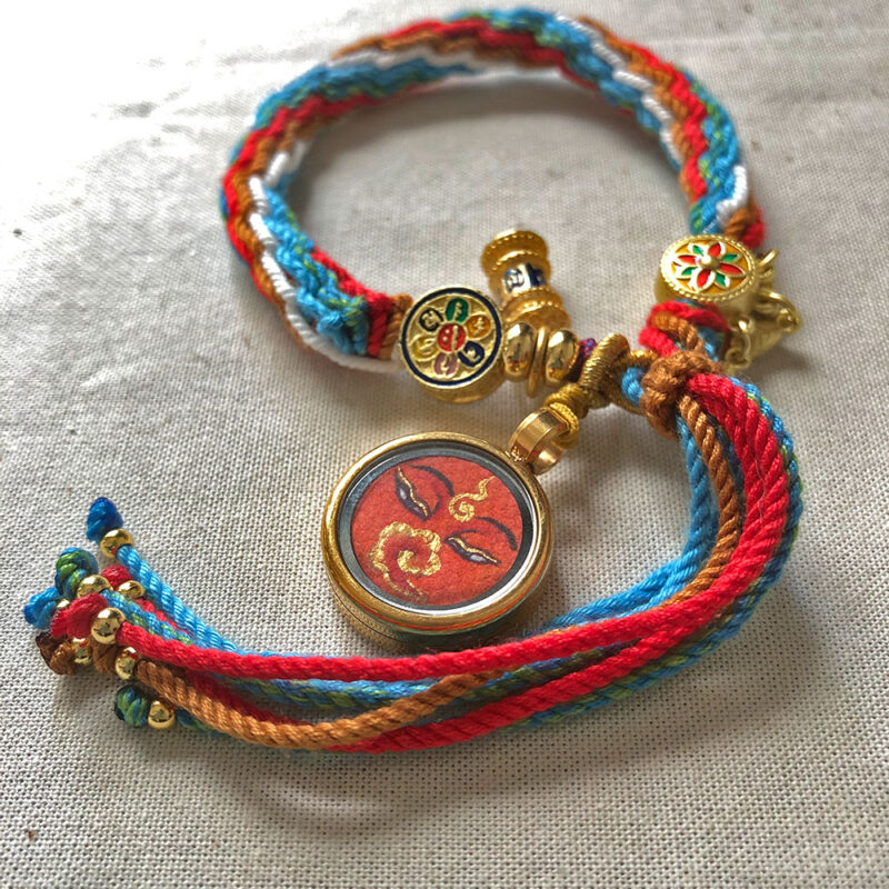 Flatlay layout of the orange Shakyamuni Buddha Eyes braided cord bracelet for mindfulness.