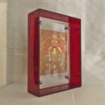 Side perspective of Shakyamuni Buddha Thangka print inside a red translucent acrylic display frame.