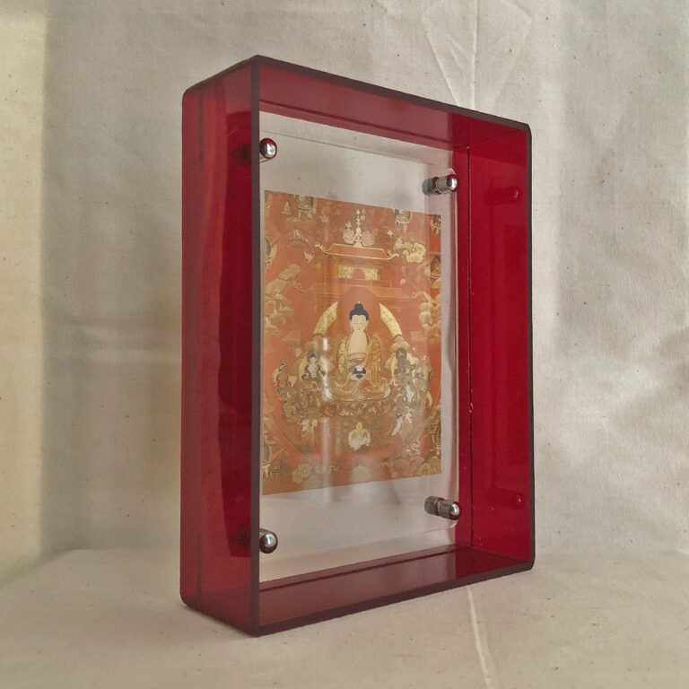 Side perspective of Shakyamuni Buddha Thangka print inside a red translucent acrylic display frame.