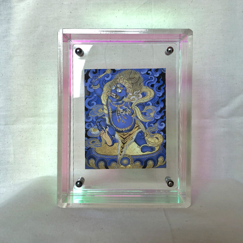 Front view of blue Vajrapani Thangka print in an iridescent rainbow floating acrylic frame.