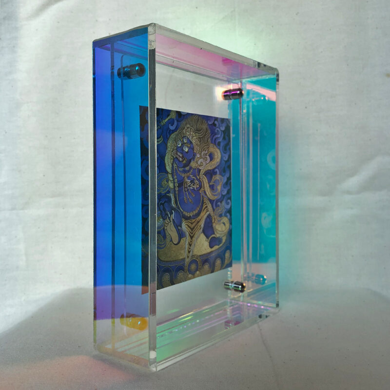 Side view of blue Vajrapani Thangka print inside an iridescent rainbow acrylic frame.