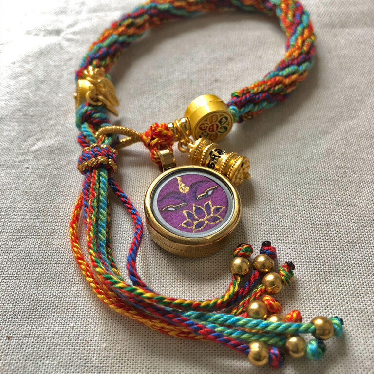 Flatlay layout of the purple Vajrasattva Buddha Eyes braided cord bracelet for meditation.