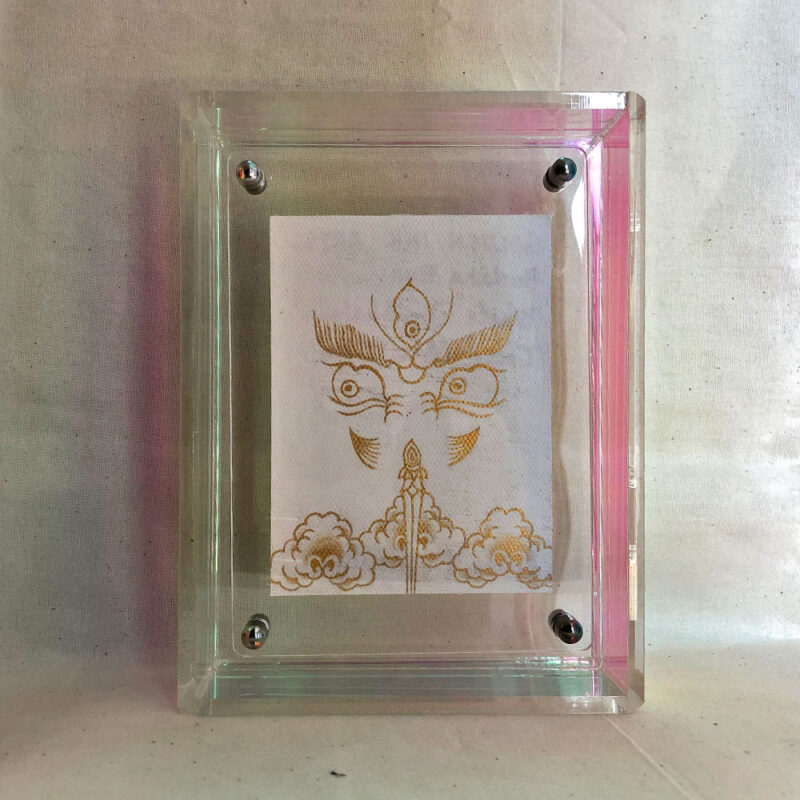 Front view of white Jambhala Buddha Eyes print in an iridescent floating translucent acrylic frame.