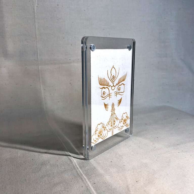 Side-angle view of freestanding clear acrylic block displaying White Jambhala line art.