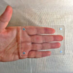 Hand holding transparent acrylic block frame showing compact pocket-sized dimensions.