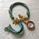 Backside view of the White Tara charm bracelet displaying the signature brand emblem.