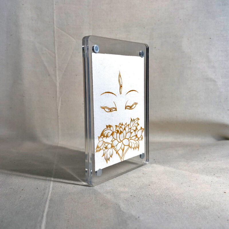 Side-angle view of freestanding clear acrylic block displaying White Tara line art.