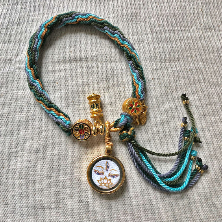 Flatlay layout of the White Tara Buddha Eyes braided cord bracelet.