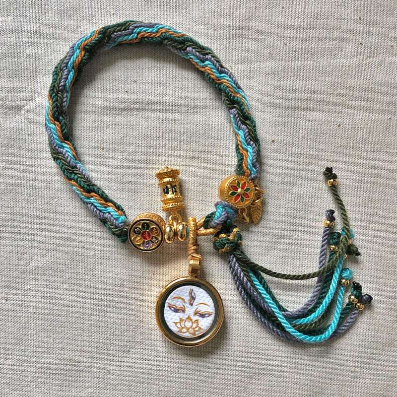 Flatlay layout of the White Tara Buddha Eyes braided cord bracelet.