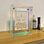 White Tara Buddha Eyes Thangka in an iridescent acrylic frame styled on a desk with essential oils.