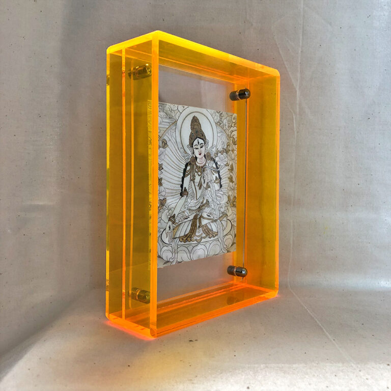 Side perspective of White Tara Thangka print inside a yellow translucent acrylic display frame.