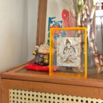White Tara Thangka yellow acrylic art block styled on a wooden cabinet next to home decor.