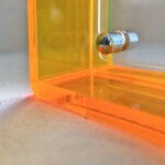 Close-up of magnetic corner screw on amber yellow translucent acrylic display block.