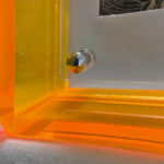 Close-up of magnetic corner screw on amber yellow translucent acrylic display block.