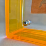 Close-up of magnetic corner screw on amber yellow translucent acrylic display block.