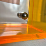 Close-up of magnetic corner screw on amber yellow translucent acrylic display block.