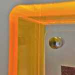 Close-up of magnetic corner screw on amber yellow translucent acrylic display block.